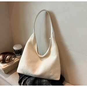 Close-up of a soft beige fuzzy hobo bag with leather strap in a cozy autumn setting