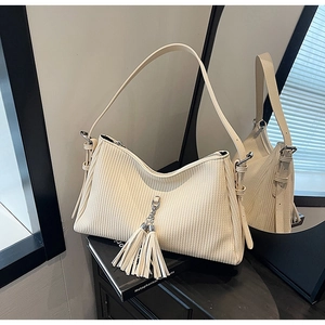 Close-up of retro cream white pleated shoulder bag with vertical stripes and tassel detail