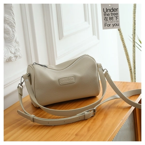 Detail of beige crossbody pillow bag with pebble leather texture and silver buckle