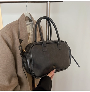 Detail of vintage black leather handbag with gold logo shown in lifestyle setting