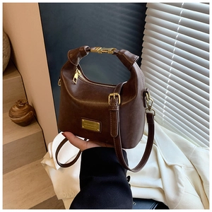 Detail of vintage brown leather handbag with gold metal plaque and arched top handle