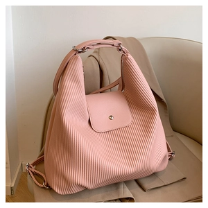 Detalle de mochila de pana rosa plisada con hebilla metálica plateada sobre blazer café