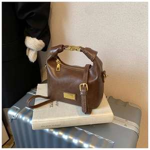 Detail view of the vintage brown leather handbag with gold metal hardware and top handle