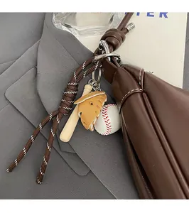Detail of baseball charm with bat, glove and ball attached to a brown leather strap