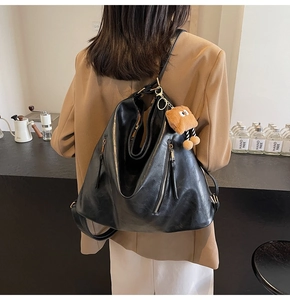 Detailed view of black soft leather convertible backpack with a brown plush toy charm