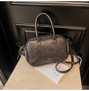 Close-up of vintage texture dark gray leather handbag with gold logo and hardware detail