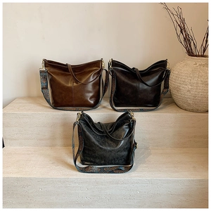 Detailed view of vintage bucket bags in brown and black with ethnic woven shoulder straps
