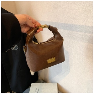 Detail of vintage brown leather handbag featuring gold H-buckle and structured top handle