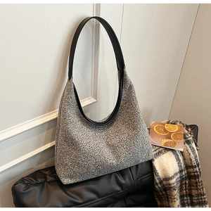 Detail of the grey tweed texture and black leather shoulder strap on the large tote bag