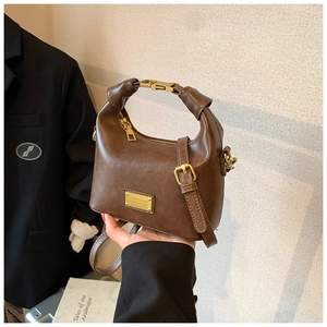 Detail of vintage brown leather handbag with gold clasp and elegant square metal nameplate
