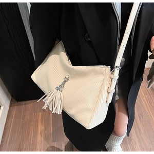 Detail of off-white pleated shoulder bag with vertical textures and long tassel charm