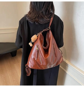 Detail view of large brown faux leather tote bag with stylish vertical metal zippers