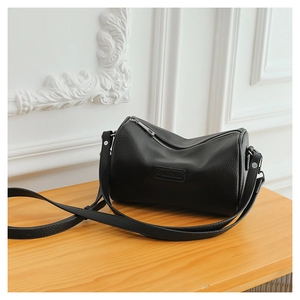 Close-up of black lychee grain leather cylinder bag with detailed metal zipper and logo