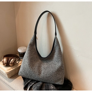 Close-up of grey tweed hobo bag with black leather strap and gold zipper detail