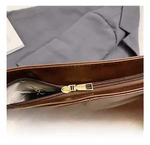 Detailed close-up of dark brown leather tote bag showing gold zipper and textile lining