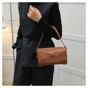 Detailed view of caramel brown barrel bag featuring lychee grain leather and logo