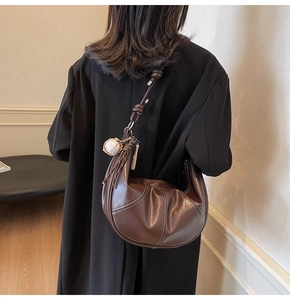 Detail of hobo bag with contrast stitching, leather knot and baseball charm