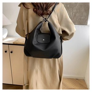 Detalle de bolso de hombro plisado negro con remache plateado en modelo en escena interior