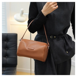Detail of brown lychee grain leather pillow bag with elegant embossed logo and zip