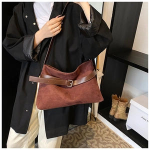 Détail du sac sous le bras en daim bordeaux avec boucle décorative en cuir marron