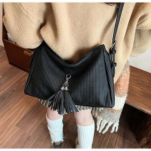 Detailed macro view of black pleated hobo bag with fringe and adjustable strap