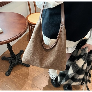 Close-up of large brown fleece shoulder bag with matte leather trim and straps