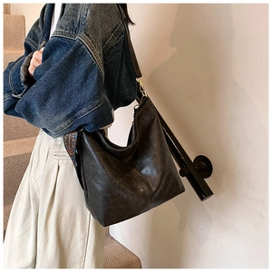 Detail of black oil wax leather hobo bag featuring a colorful woven shoulder strap