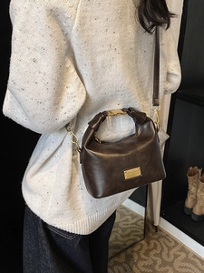 Vintage dark brown glossy leather handbag for women shown from back view on model