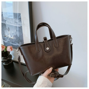 Détail d'un sac seau vintage marron foncé en simili cuir lisse avec fermoir métallique