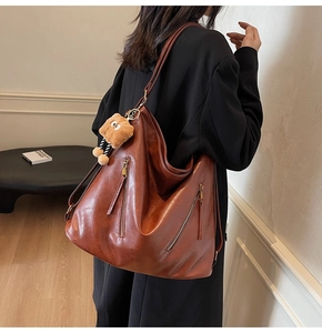 Detail view of large dark brown leather tote bag with functional vertical metal zippers