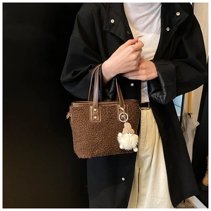 Detail of brown plush bucket bag with teddy fleece texture and cute white doll pendant
