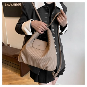 Detalle del bolso tote de cuero plisado beige con cierre de solapa magnética semicircular