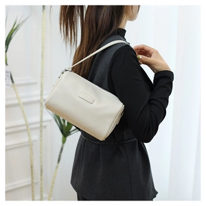 Close-up of cream leather pillow bag showing the litchi grain texture and metal zipper