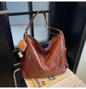 Detail view of dark brown PU leather tote with vertical zippers and plush bear charm
