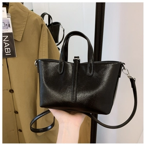 Détail d'un sac cabas noir vintage en cuir brillant avec boucle décorative et bandoulière