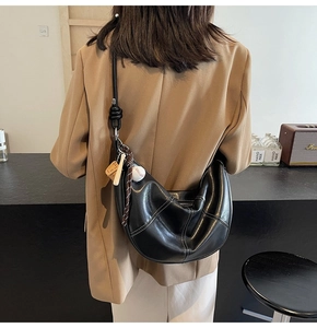 Detail of black crescent shoulder bag with white contrast stitching and knot detail