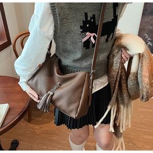 Detail of dark brown pleated texture shoulder bag with stylish metal chain tassel pendant