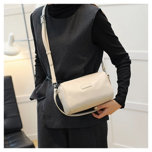 Side view of beige lychee leather cylinder bag on model showing size and texture