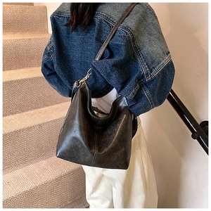 Deep brown retro leather bucket bag with contrast stitching and long strap detail