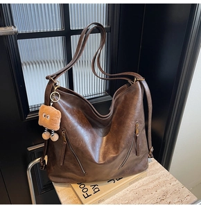 Detail of dark brown hobo bag with vintage leather texture and dual front zippers
