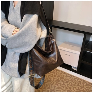 Detail of deep brown leather bucket bag featuring a bohemian print wide shoulder strap