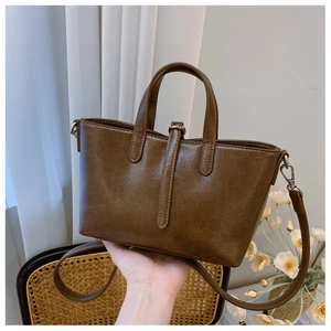 Vue détaillée du sac seau marron rétro montrant la texture cuir et boucles en métal