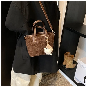 Brown fuzzy bucket bag with leather strap worn crossbody for autumn winter style
