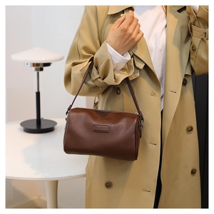 Detailed view of dark brown pebbled leather texture on a vintage Boston style handbag