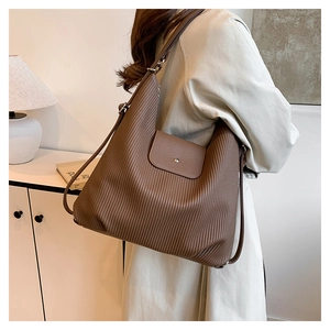 Detalle del bolso hobo marrón con textura de rayas verticales y hebilla de metal en cuero PU