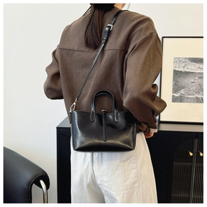 Détail du sac seau noir brillant avec ferrures argentées et bandoulière réglable