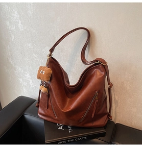 Detailed texture of brown PU leather tote bag with dual zippers and plush bread charm