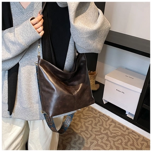 Close-up of brown faux leather bucket bag with retro patterned bohemian wide strap