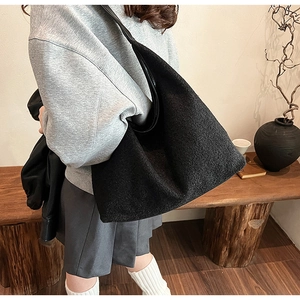 Detail view of large black wool tote bag showing thick fuzzy texture on a shoulder strap