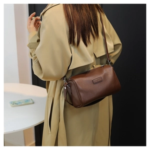 Detail of dark brown pebble leather Boston bag styled with a minimalist trench coat